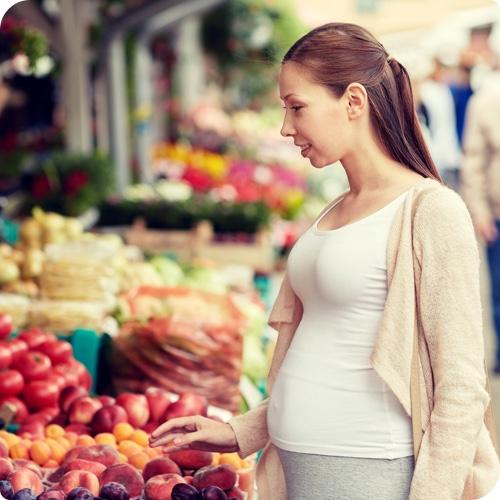 Woman browsing fruit at market looking for best foods for heartburn.